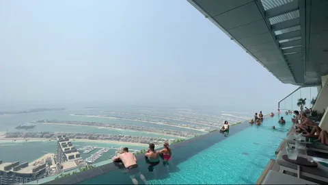 Wide infinity pool scene with guests overlooking Palm Jumeirah in Dubai