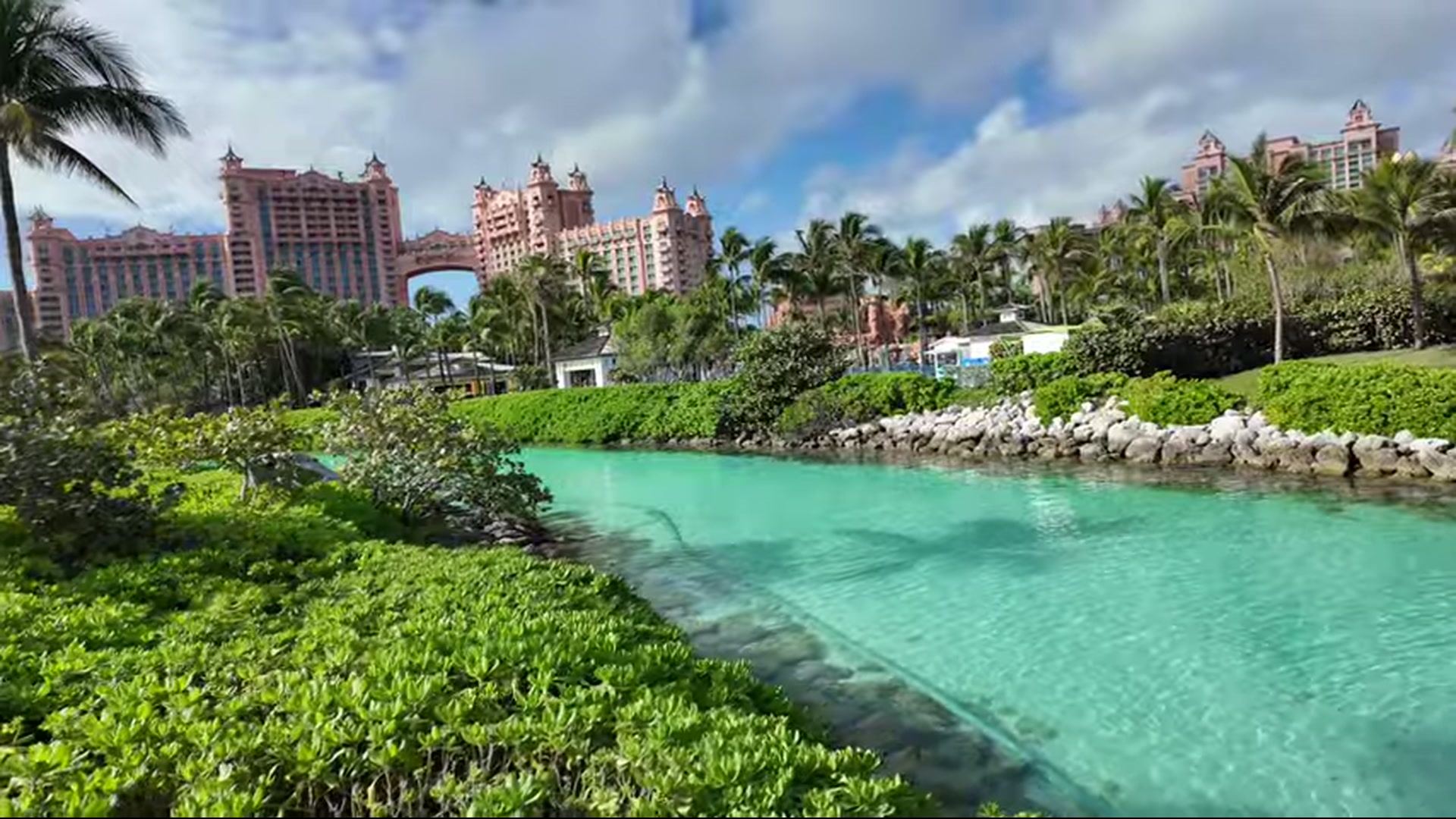 Atlantis resort complex with a bright turquoise water channel and lush greenery.