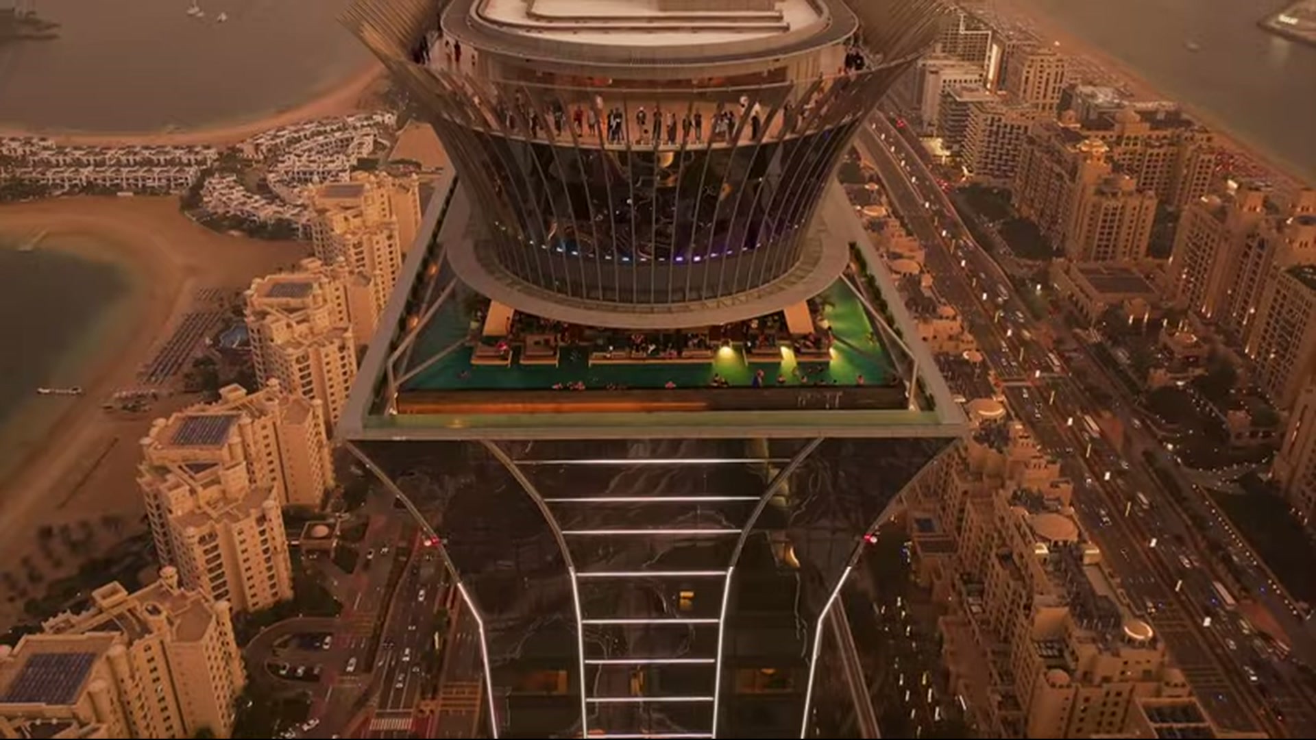 Aerial view of the tower housing Aura Skypool above Dubai shoreline and roads