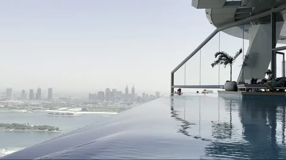 Боковой вид бассейна с пальмой, стеклянным углом и skyline.