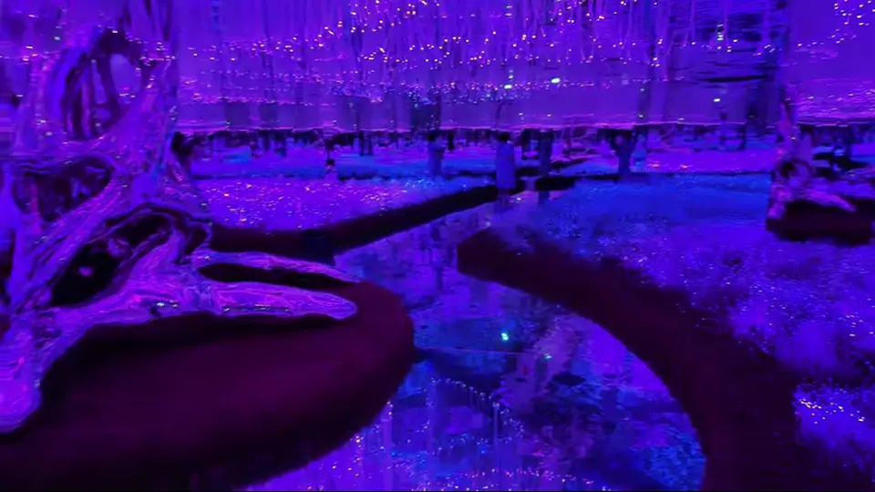 Chrome tree sculpture rises among glowing purple garden paths.