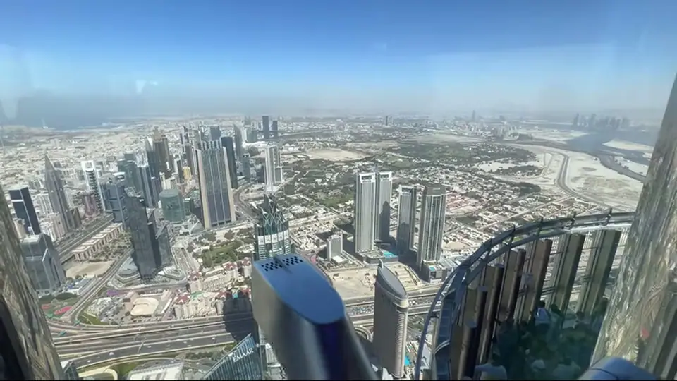 Wide daytime view of Dubai skyline from deck with curved railing.