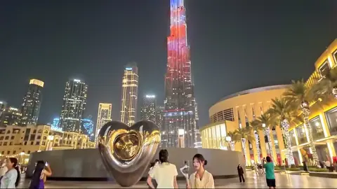 Burj Khalifa lit red, white and blue above heart sculpture at night.
