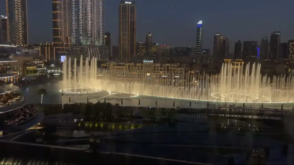 Burj Khalifa with colorful projections at night among lit downtown towers.