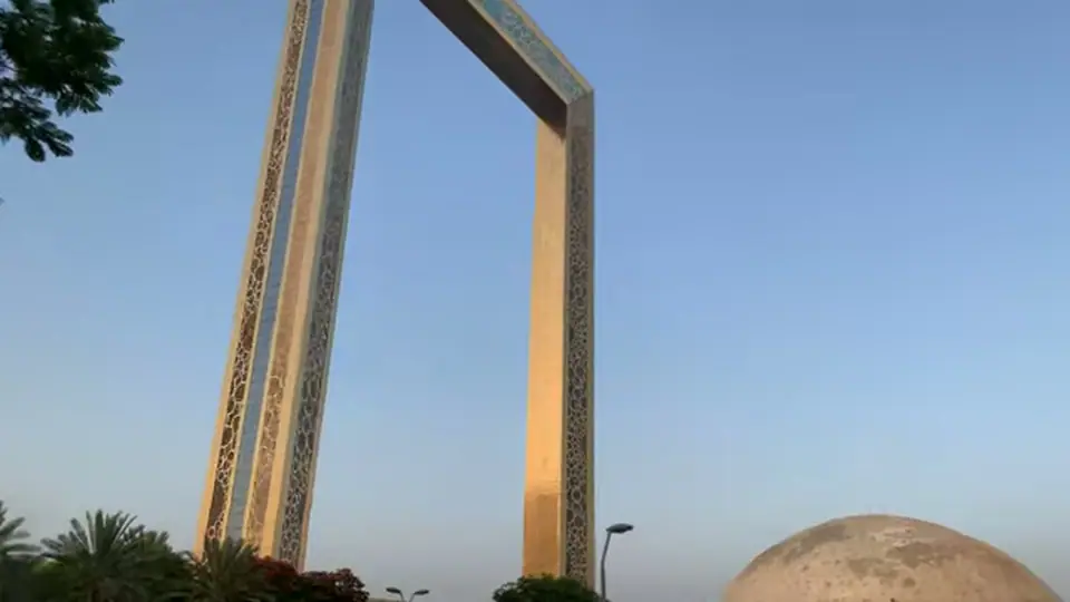 Massive fireworks burst over Dubai Frame as crowd films below.