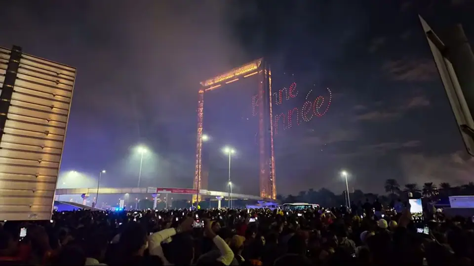 Low-angle view of Dubai Frame rising into bright blue sky.