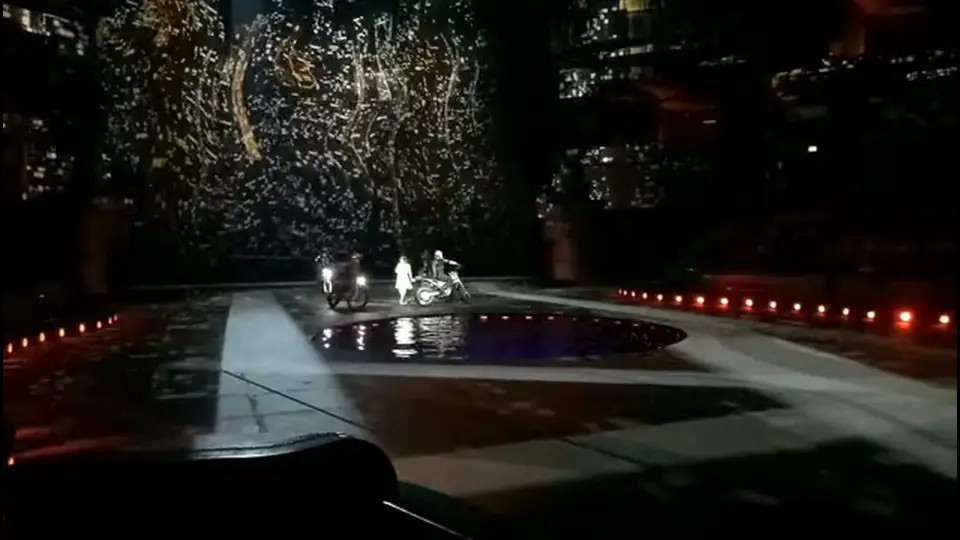 White-clad performer stands beside motorcycles near the reflecting pool.
