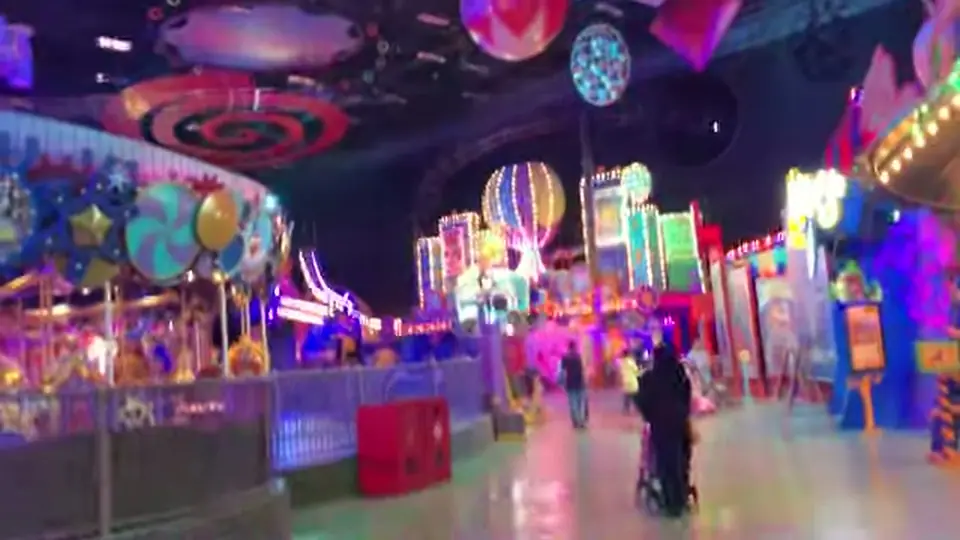 Indoor avenue with colorful facades, balloons, and glossy reflective floor.