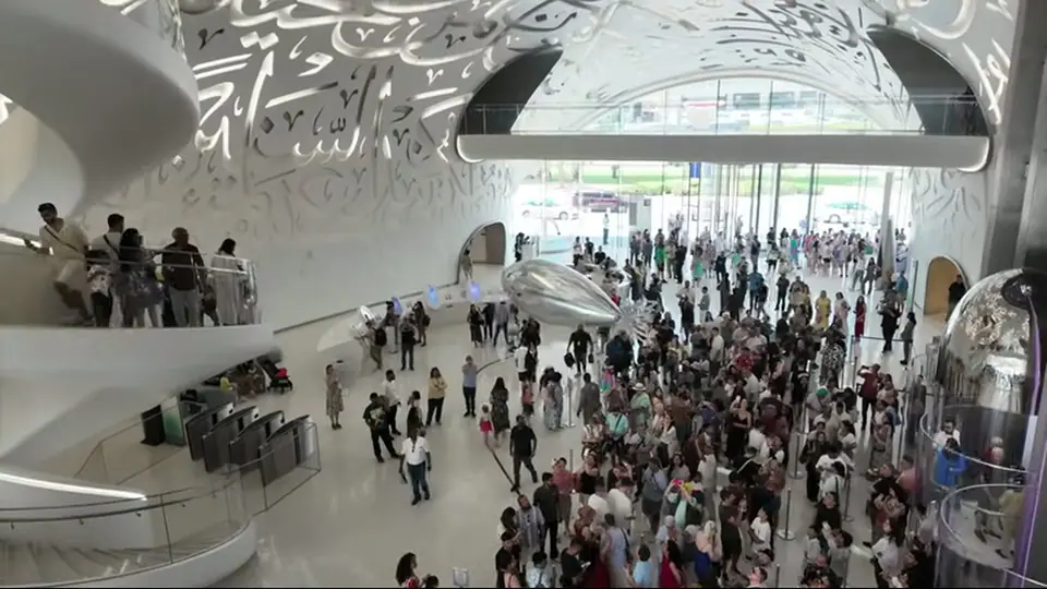 Low-angle view of the Museum of the Future with palms and sun behind.