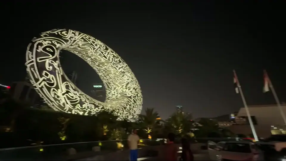 Ground-level view of the Museum of the Future with palms and curved grassy entrance.