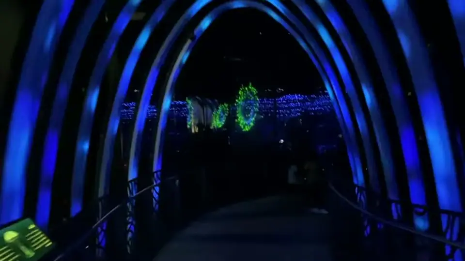 Glowing blue arches lead toward green forms in darkness.