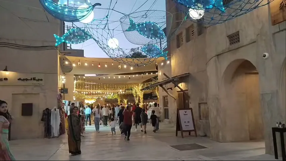 Visitors walking through a heritage-style promenade with fish lights overhead