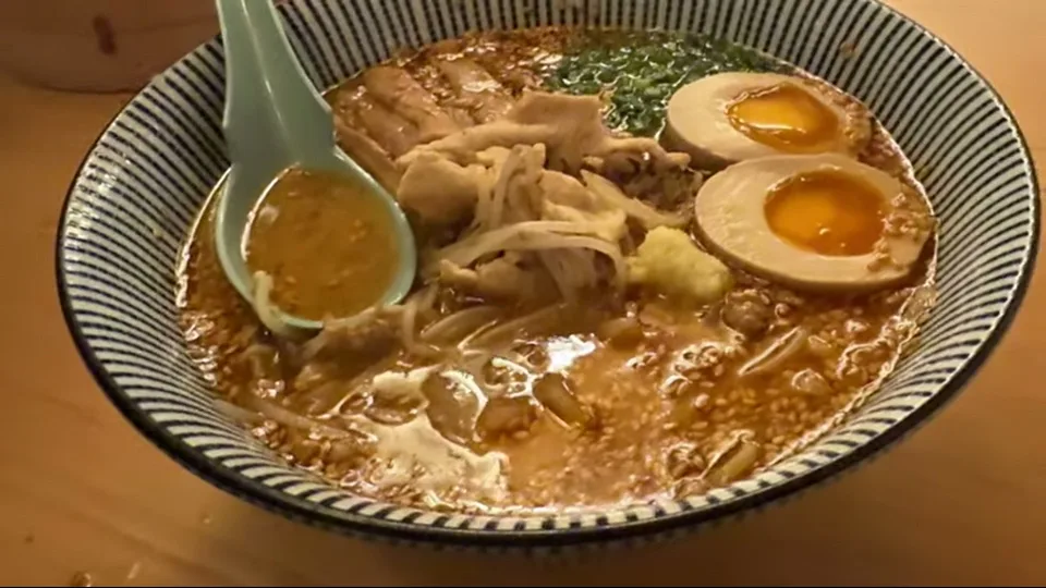 Close-up of a steaming ramen bowl with eggs, noodles, and sliced meat