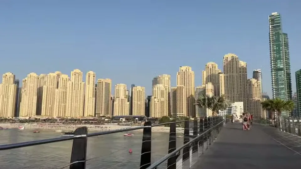 Wide boardwalk view across water to JBR and Dubai Marina towers