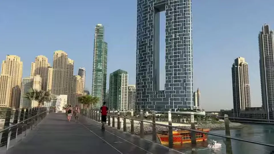 Bridge walkway leading toward Dubai Marina towers over canal