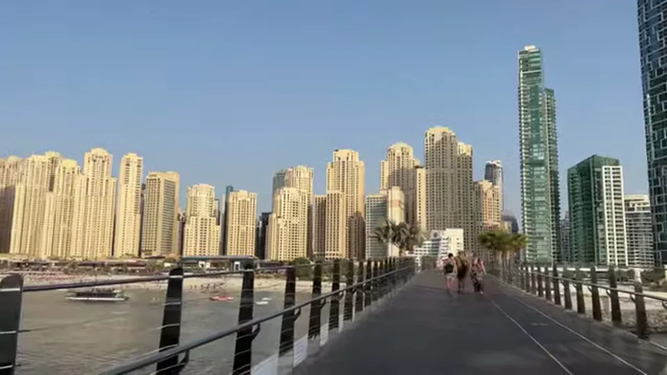 Pedestrian bridge facing a dense waterfront skyline under clear daylight