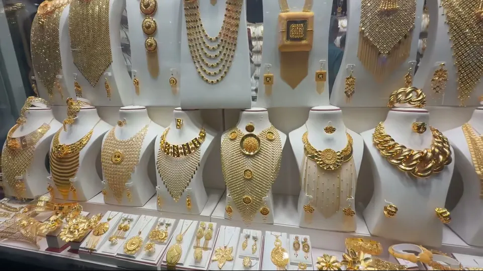 Wall of elaborate gold necklaces and matching jewelry sets on white display busts