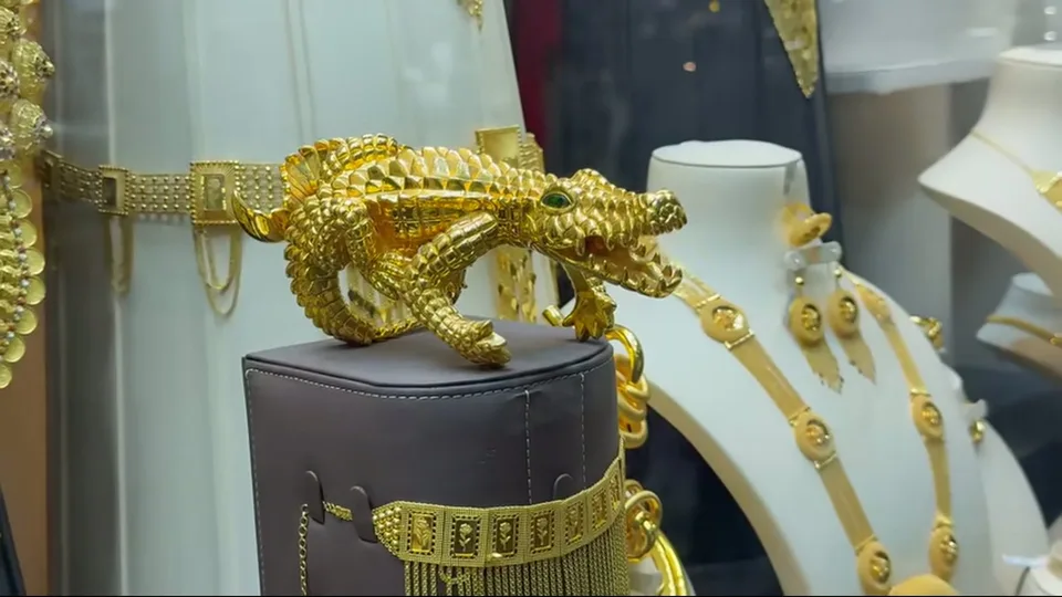 Gold crocodile-shaped ornament displayed among jewelry pieces in Dubai Gold Souk