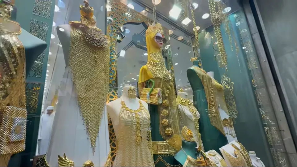 Wide jewelry display with mannequins dressed in ornate gold pieces at Dubai Gold Souk