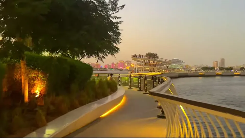 Lit creekside walkway leading to a spiral lookout platform at sunset