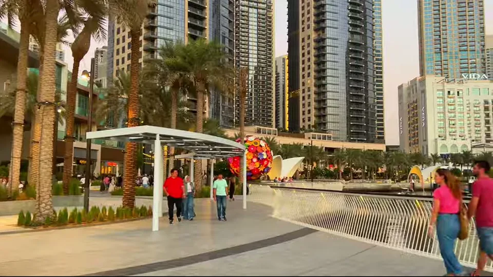 Daylight promenade with towers, VIDA hotel and colorful art sphere